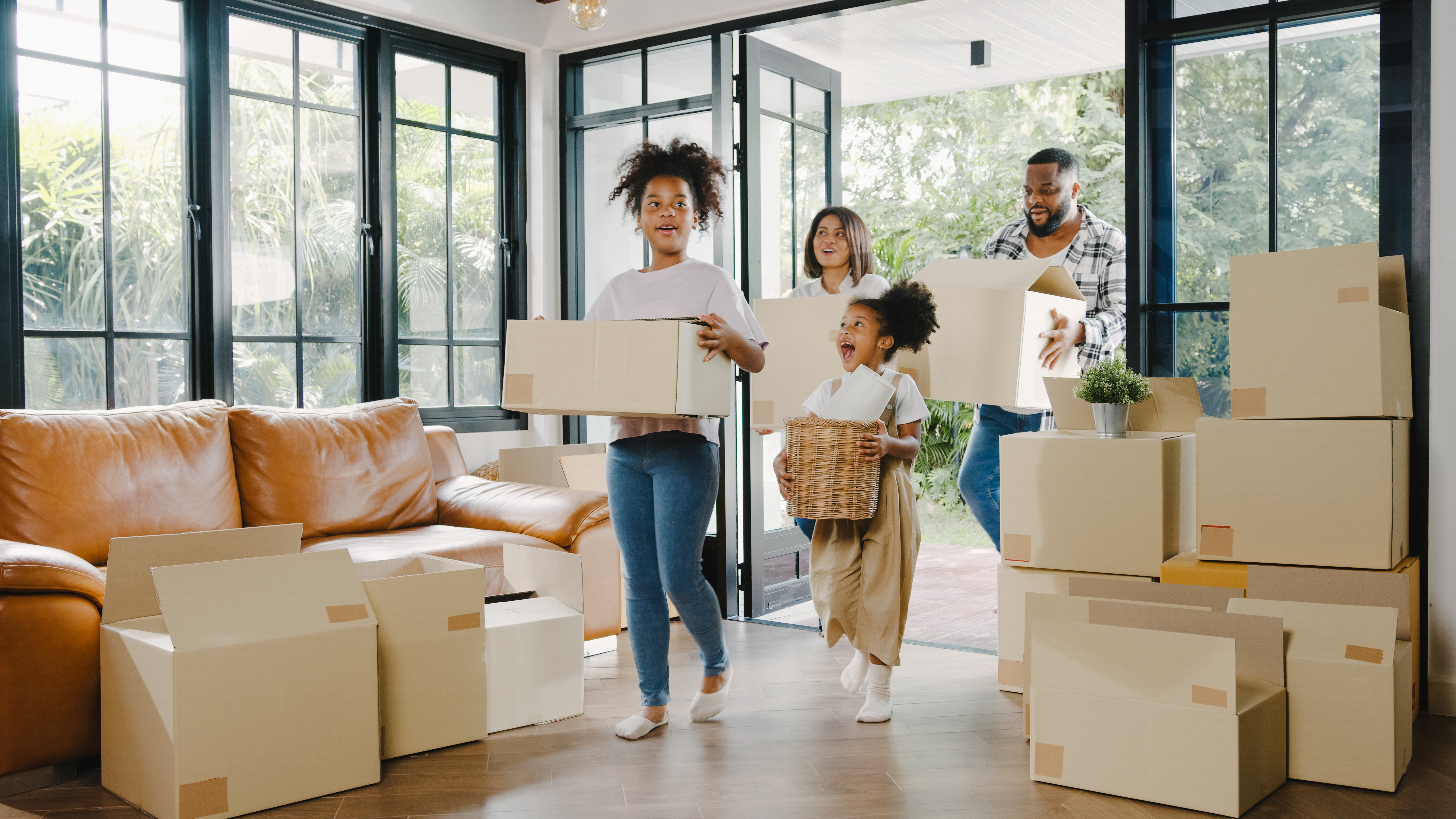 A family carrying moving boxes into their new home